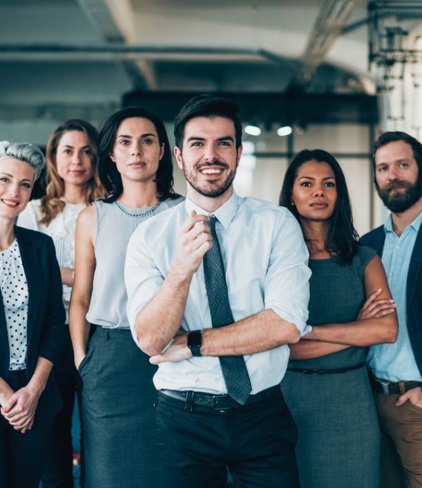 Gruppe von sechs Geschäftspersonen, die selbstbewusst und professionell in die Kamera schauen, der Mann in der Mitte steht lächelnd im Vordergrund.